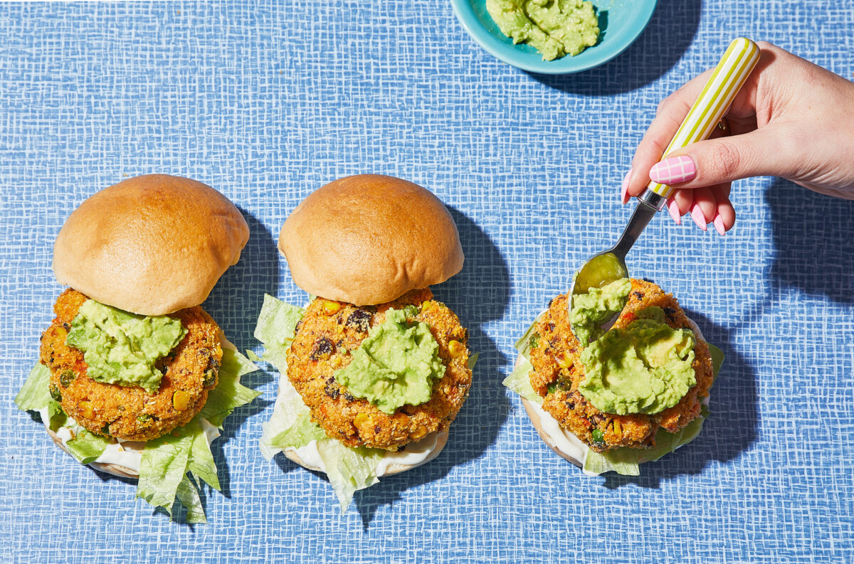 Spicy black bean burger served with a drizzle of avocado cream sauce and toasted buns.