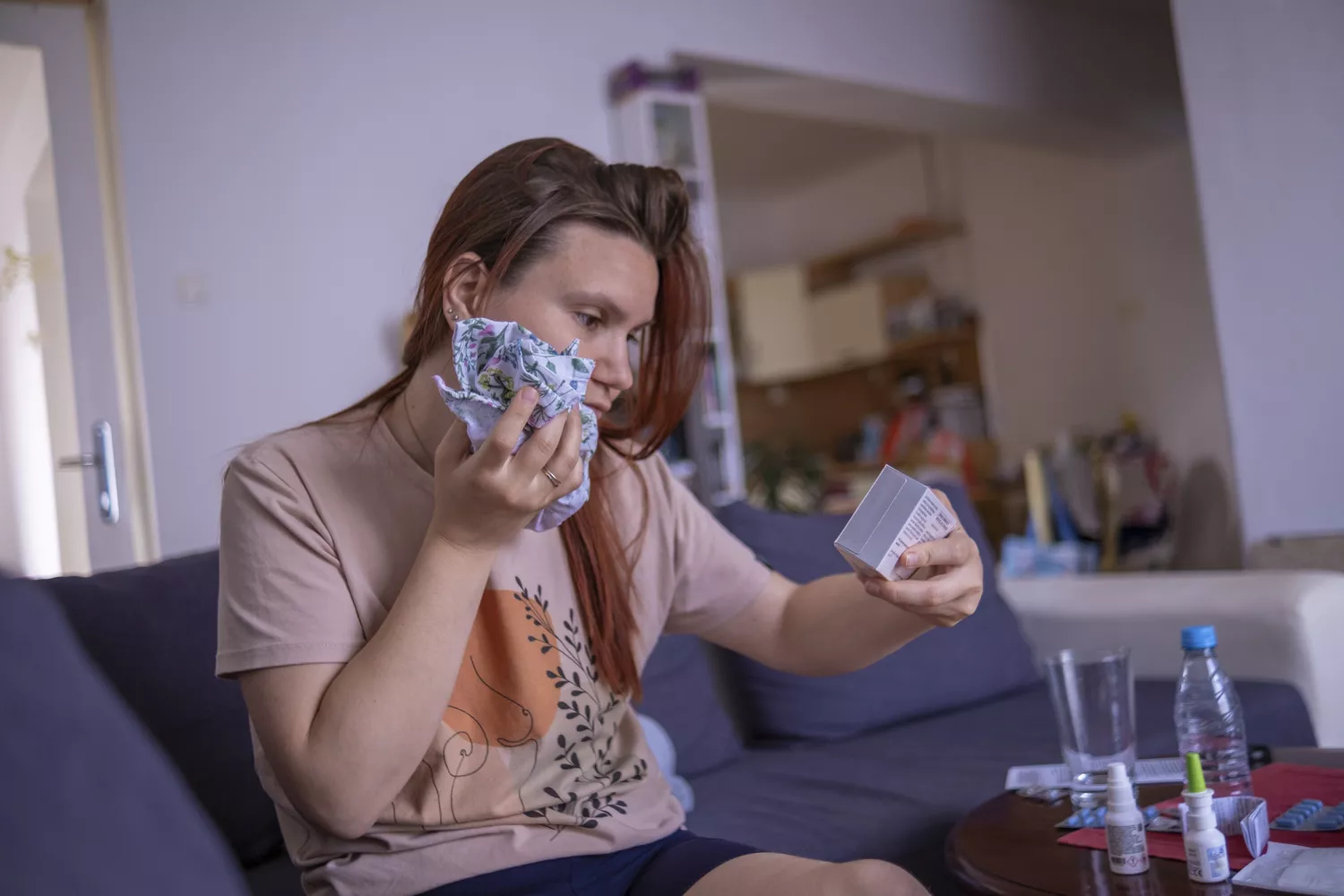 A woman holding a cold compress to her face, illustrating a moment of physical discomfort and self-care.