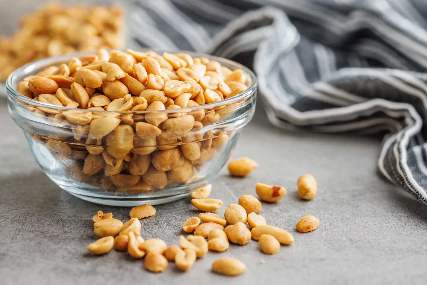 A small glass bowl filled with roasted peanuts.