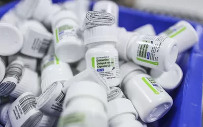 A collection of various prescription pill bottles including Duloxetine in a blue storage bin.