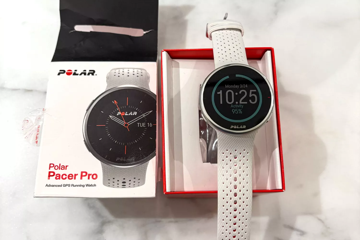 A Polar Pacer Pro GPS watch next to its retail packaging showing activity metrics.