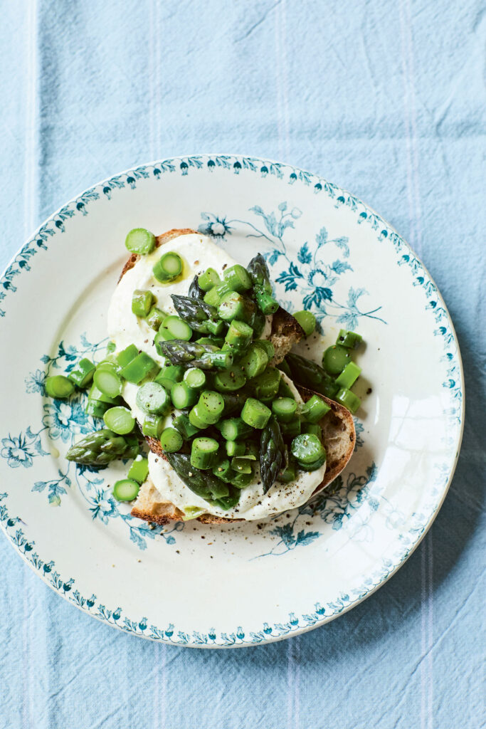 A clear bowl of spring vegetable soup featuring white cannellini beans and fresh herbs.
