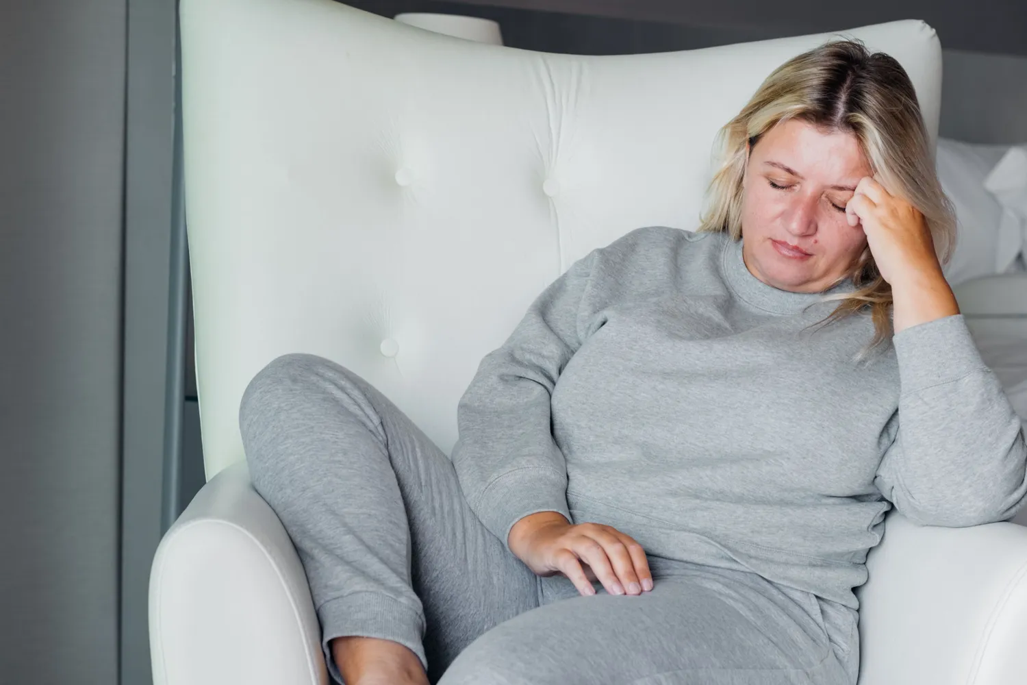 A woman holding her head in discomfort, depicting the struggle with fatigue or malaise.
