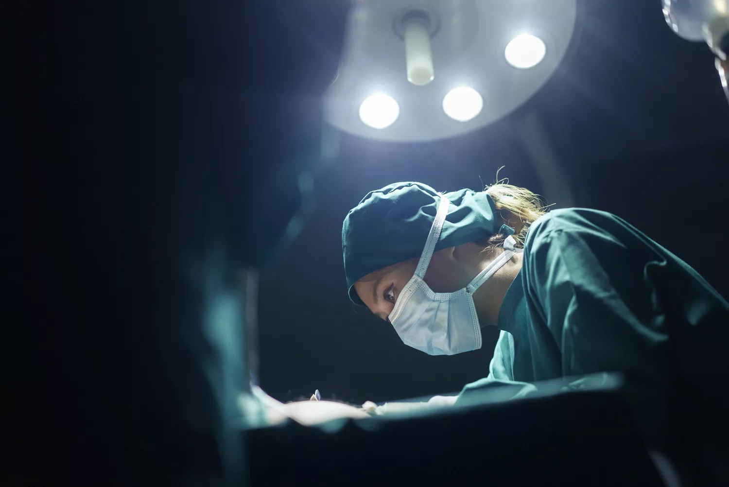 A surgeon performing a delicate procedure in a modern, sterile operating room environment.