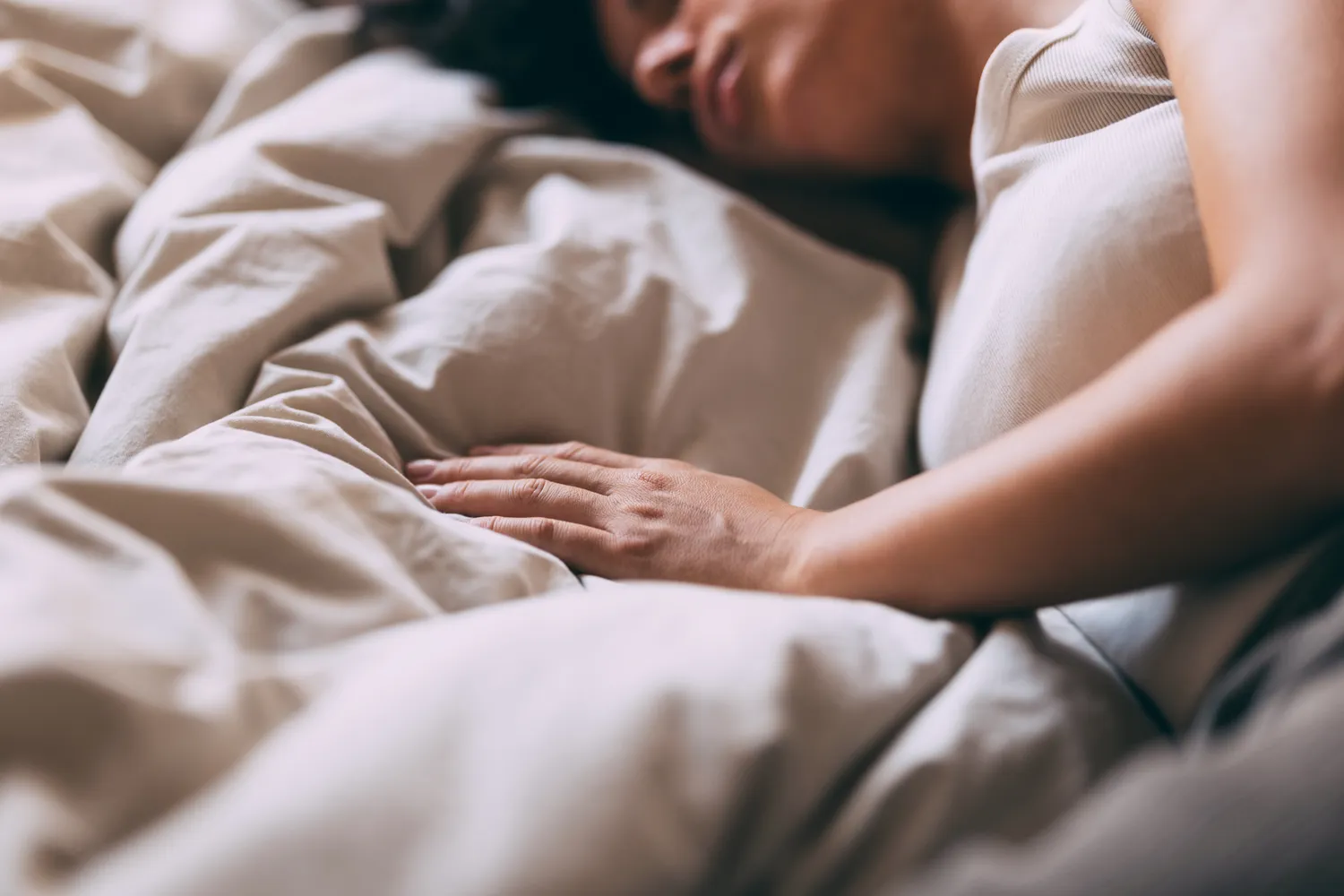 A person resting under neutral bedding to highlight health-focused recovery habits.