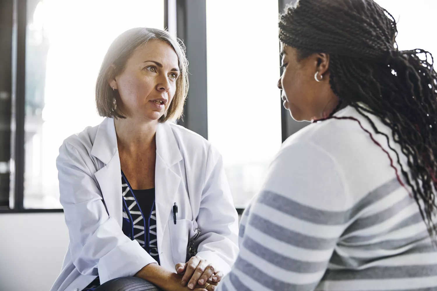 A woman talking to a doctor in a medical office to discuss her sinus symptoms.