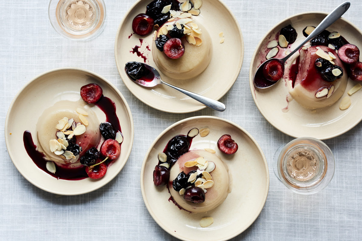 Close-up of a dairy-free almond panna cotta with a thick layer of dark red cherry sauce on top.