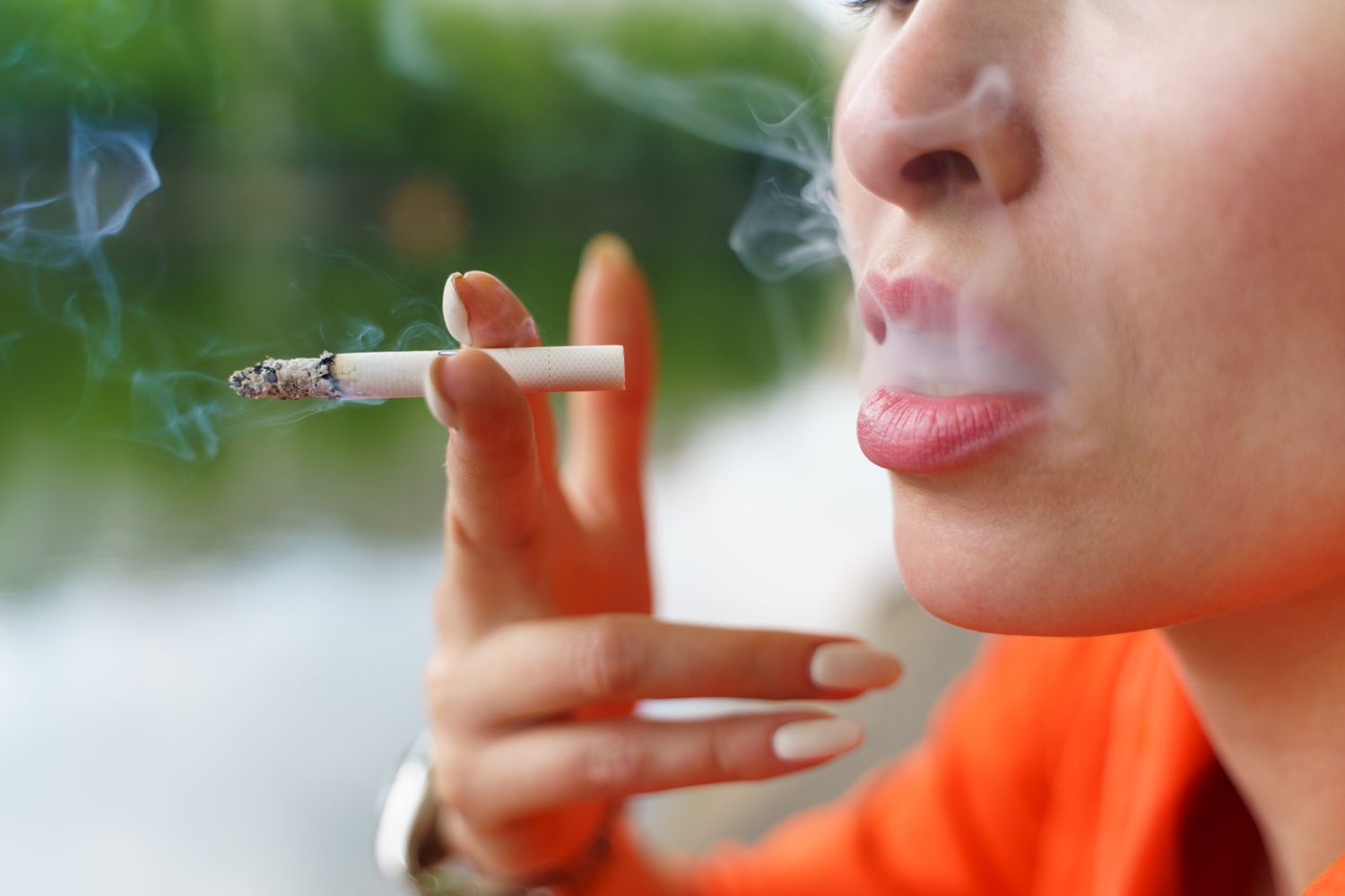A person holding a lit cigarette, representing lifestyle habits that affect cardiovascular and metabolic health.