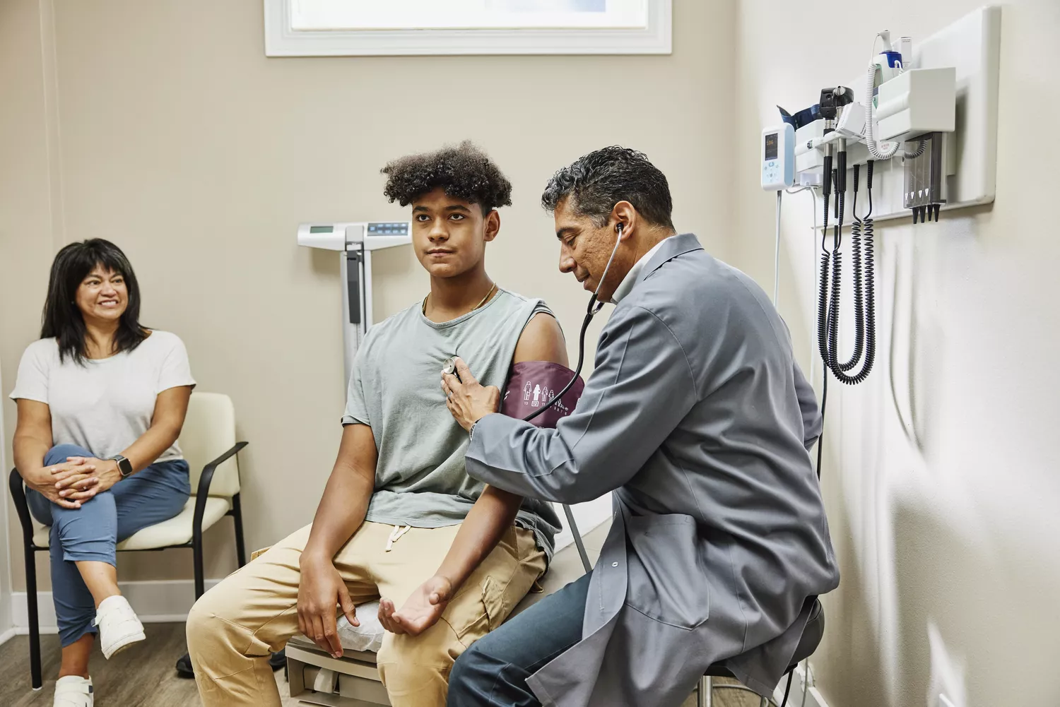 A healthcare professional using a stethoscope to examine a patient in a clinical setting.