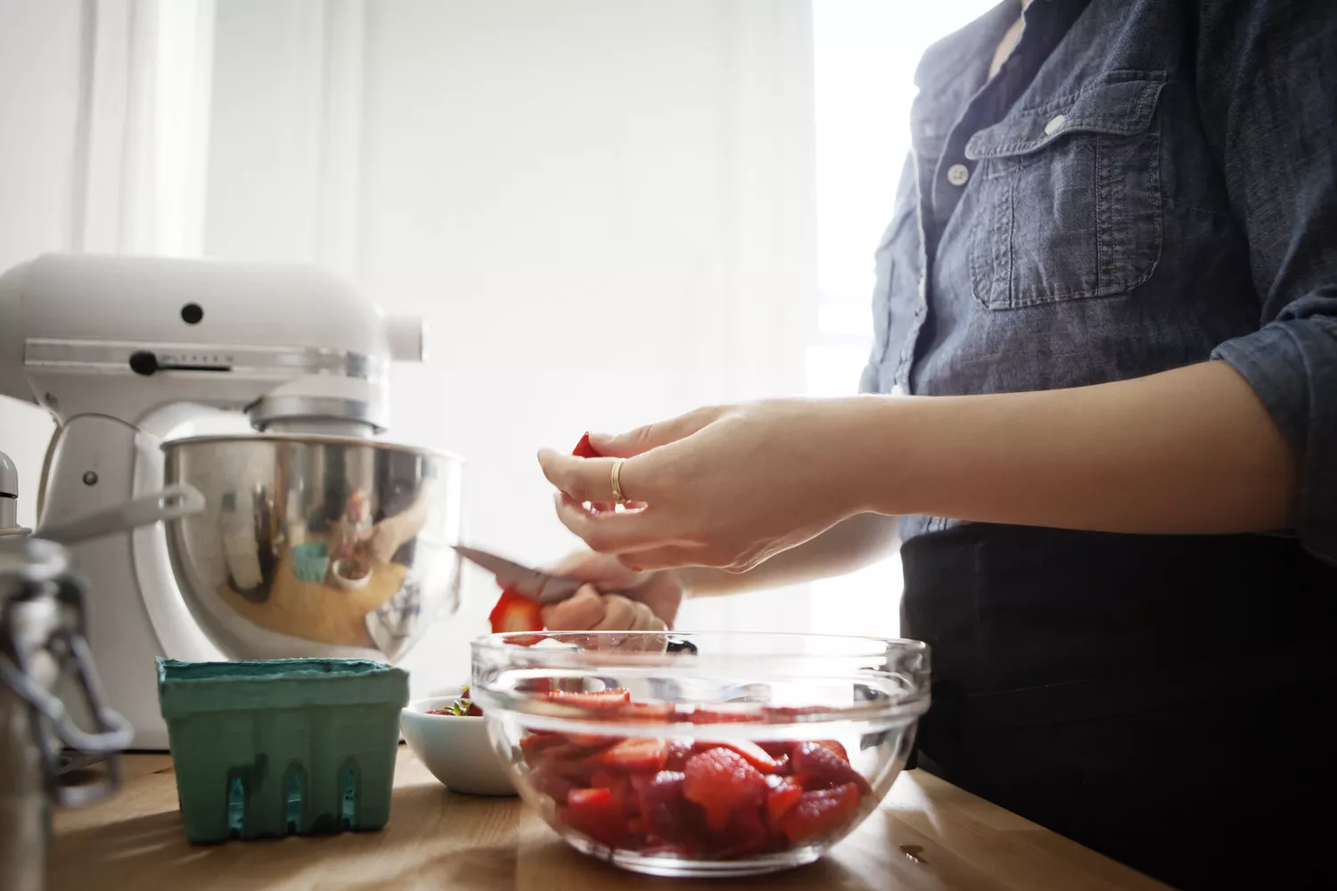 A woman preparing fresh fruit in a kitchen setting.