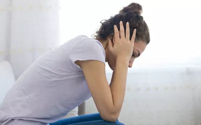 A woman sitting with her head in her hand looking distressed.