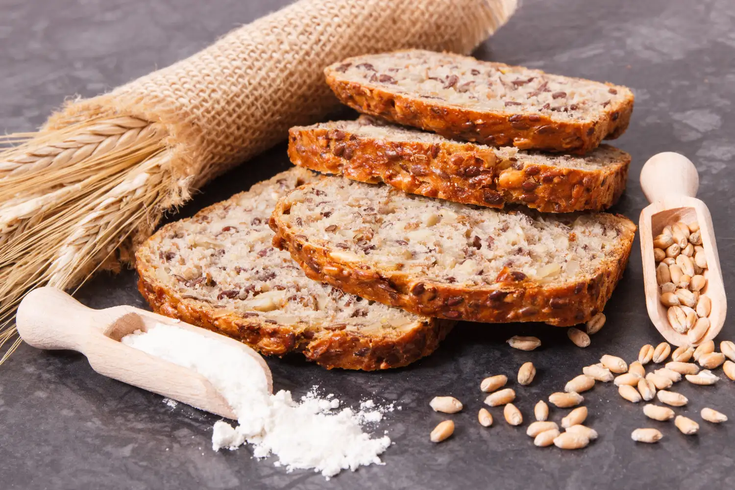 Sliced whole grain bread with seeds and wheat stalks, highlighting high-fiber ingredients.