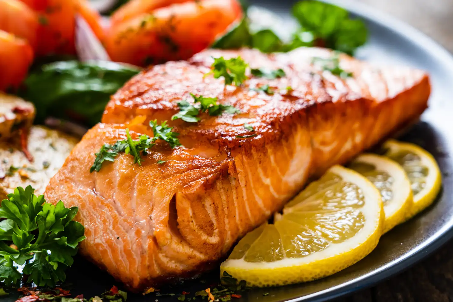 Grilled salmon served with lemon slices and green vegetables.