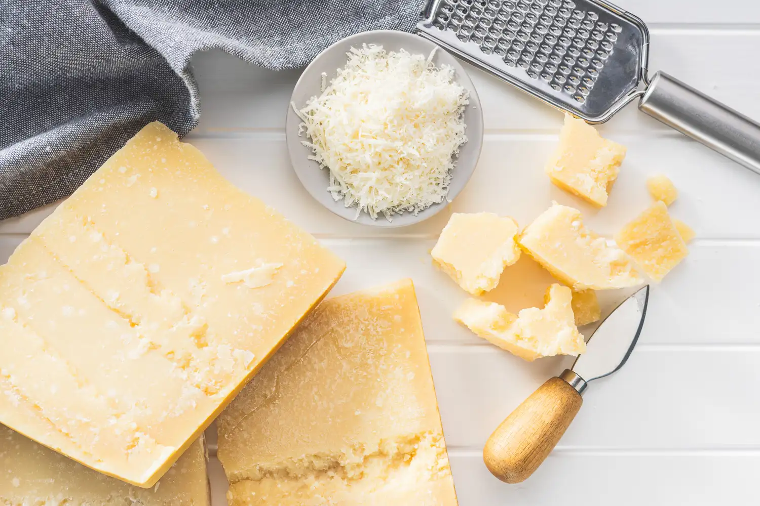 Various blocks and grated pieces of cheese with a cheese slicer.