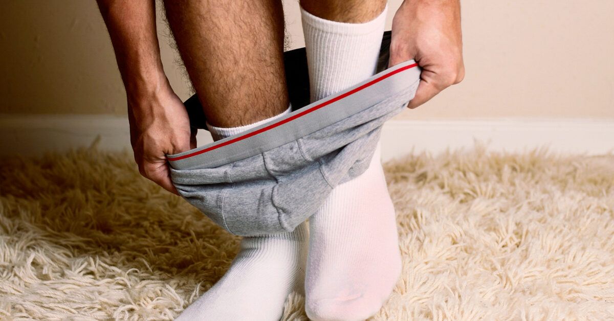 A man dressing in clean underwear to illustrate recovery and hygiene protocols.