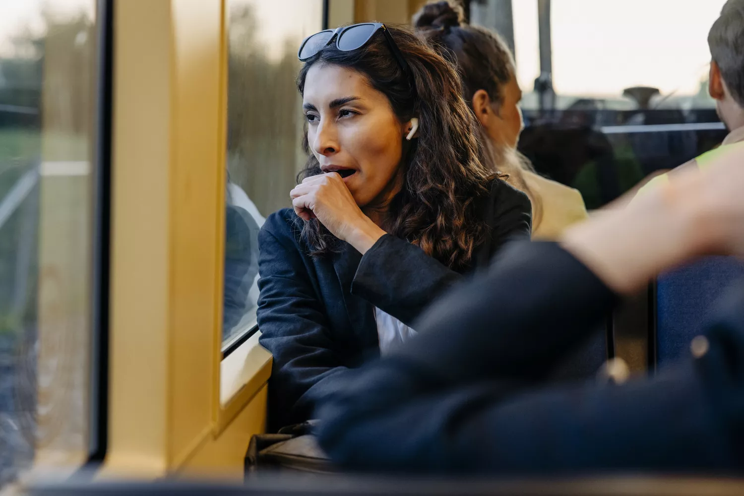 A person in a bright indoor setting yawning during the daytime.