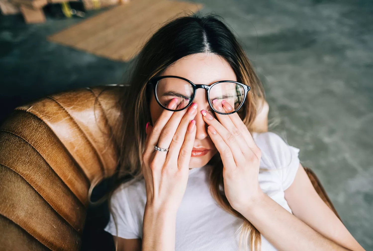 A woman looking tired and rubbing her eyes while sitting in bed.