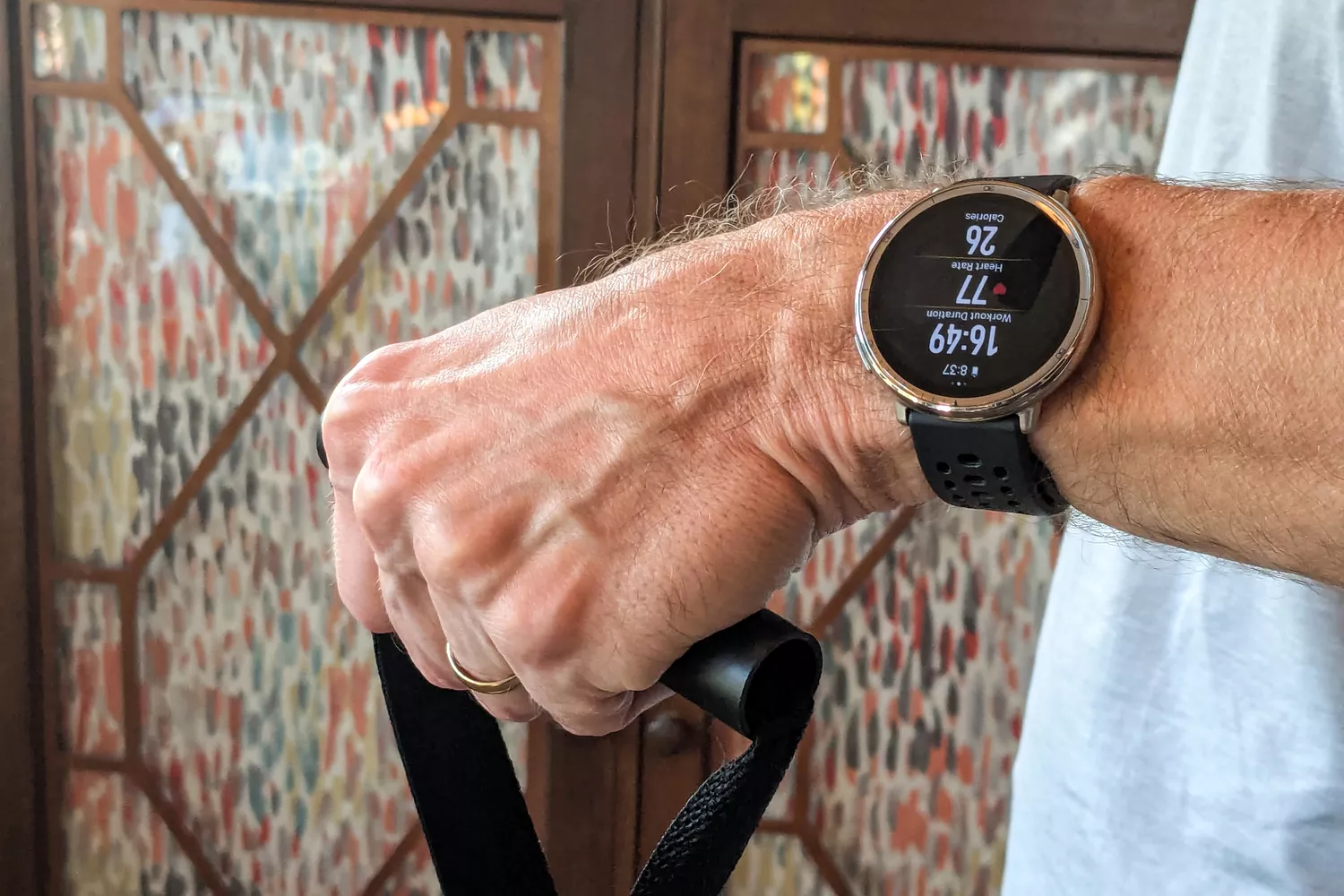 A man wearing a smartwatch while performing a resistance band workout to monitor calories and heart rate.