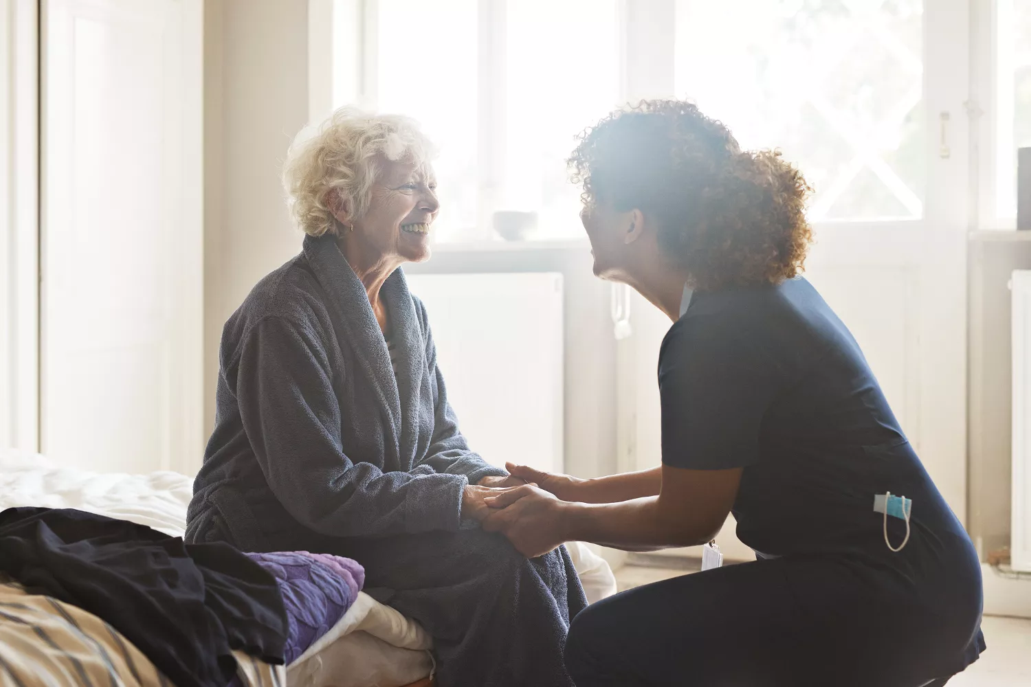 A female healthcare professional in a clinic discussing spinal health and recovery timelines with an older patient.