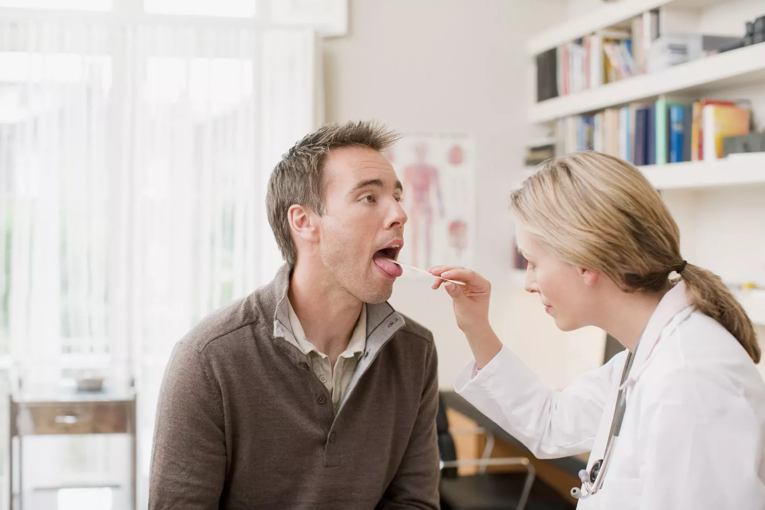 A healthcare provider examining a patient's throat and oral cavity using professional tools.