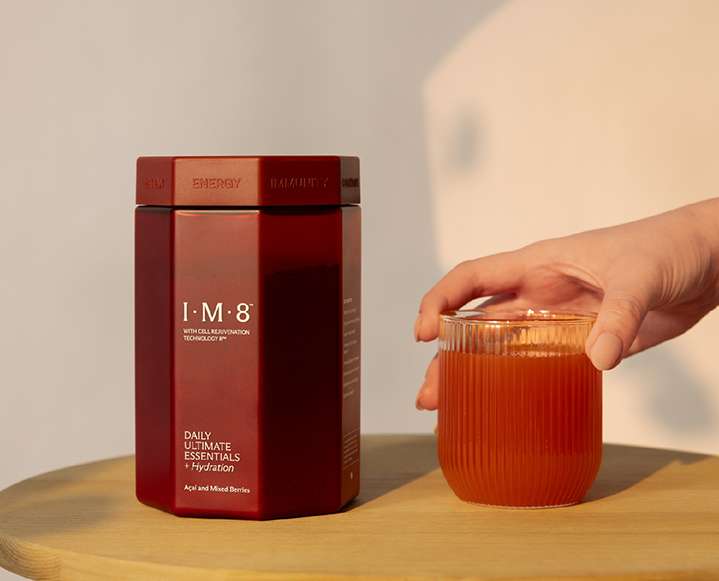 A glass of prepared IM8 supplement showing its natural berry and chocolate color profile.