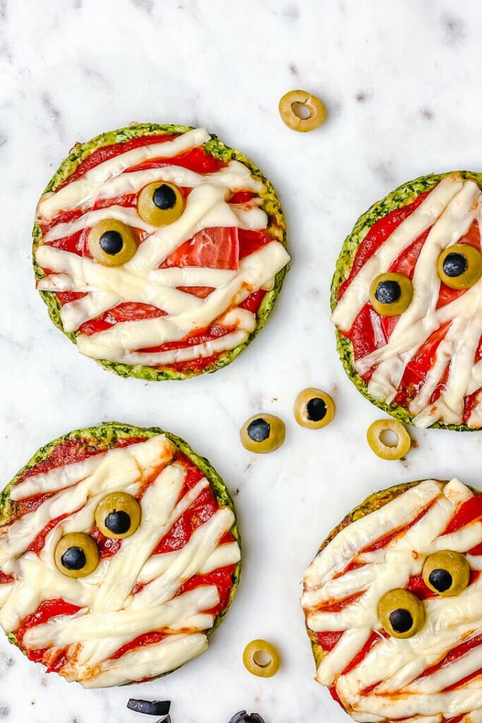 Mini pizzas with cheese strips arranged like mummy bandages and olive slice eyes.