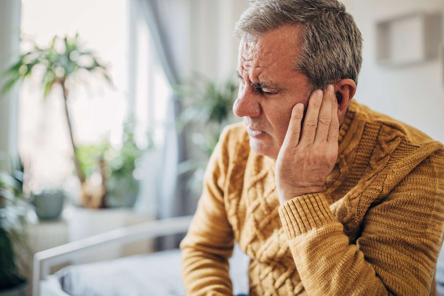 A man holding his hand to his ear in a gesture of sensory overwhelm or trying to focus.
