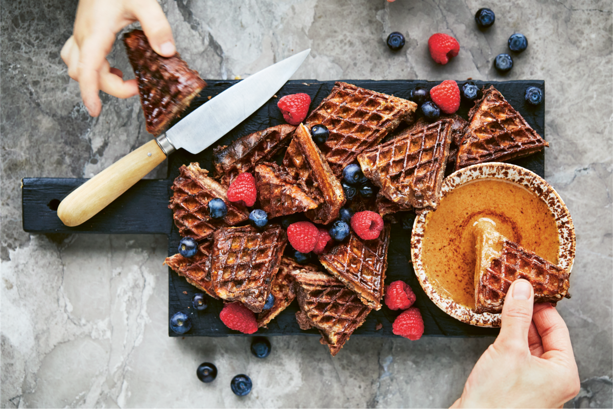 Chocolate Waffle Toast being dunked into a jar of creamy homemade granola butter.
