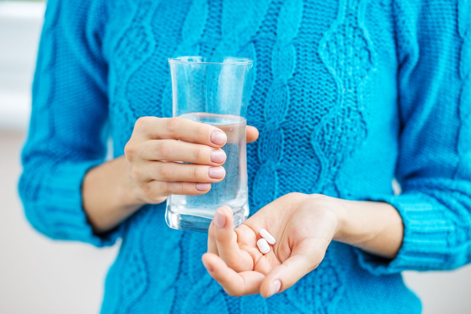 Tablets and a glass of water on a table.