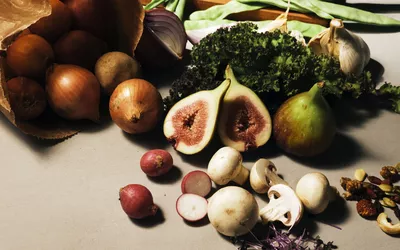 A variety of fresh vegetables and whole foods including kale, mushrooms, and radishes.