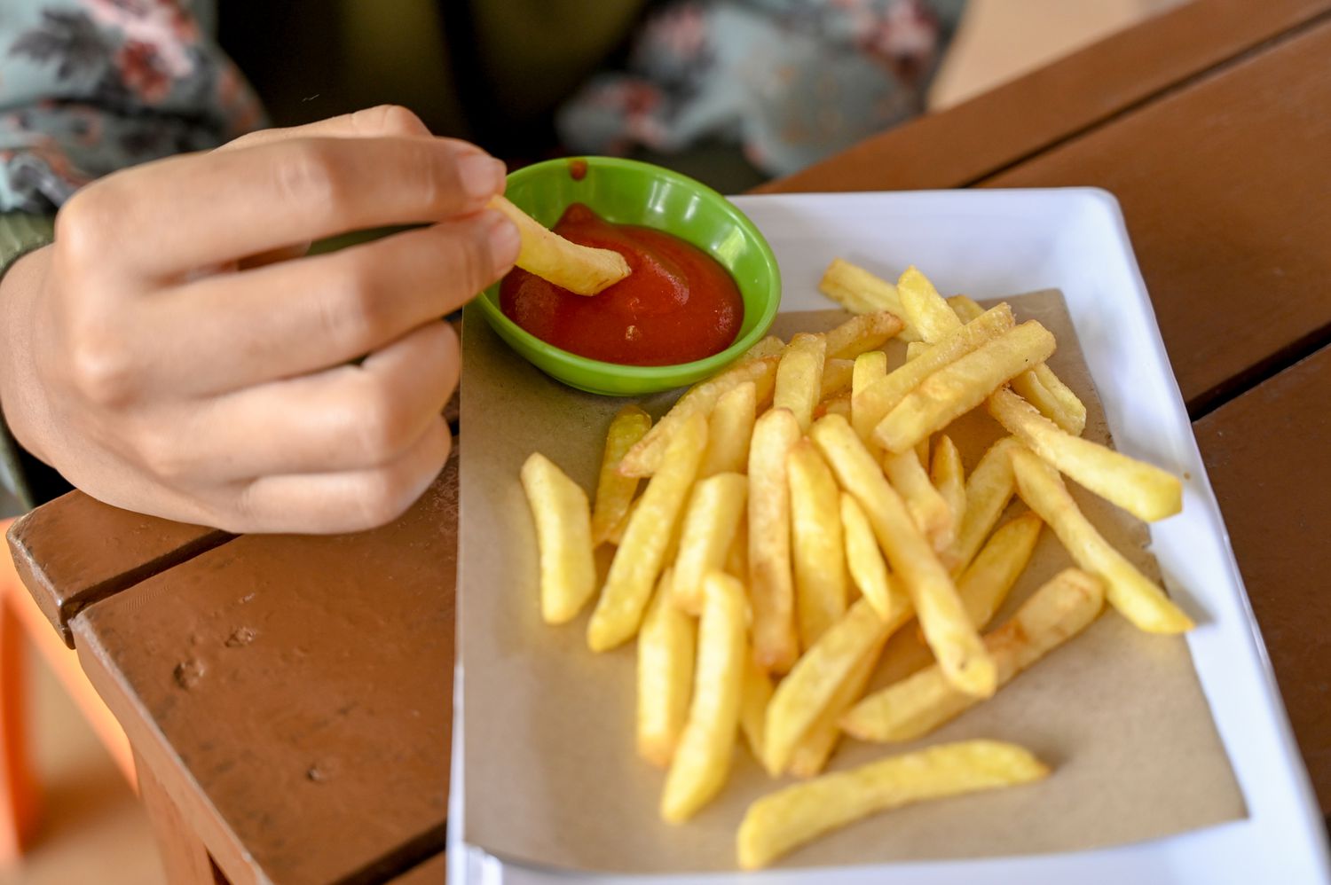 A basket of salty french fries with a side of ketchup.