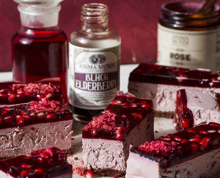 A slice of no-bake pomegranate rose jelly cheesecake showing the distinct layers of crust, cream, and elderberry glaze.