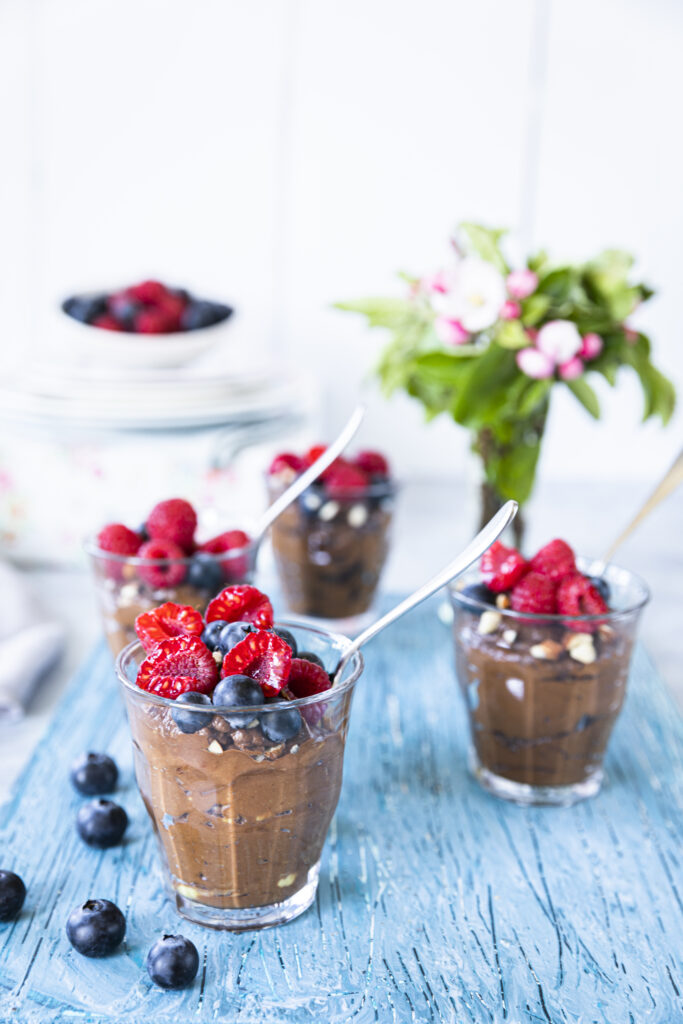 A close-up of overnight oats topped with flax seeds and mixed berries in a glass jar.