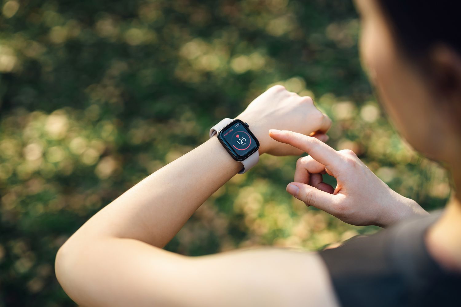 A woman checking heart rate data on her smartwatch, representing the use of objective digital metrics in health monitoring.
