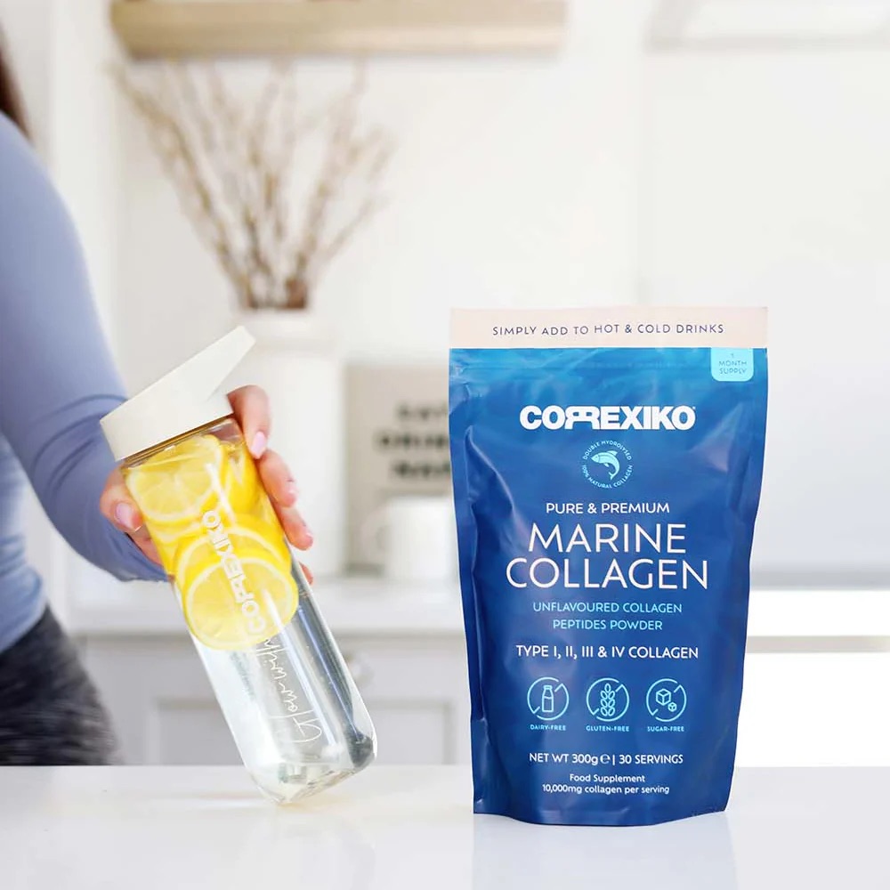 Assorted supplement capsules and a glass of water on a clean surface.