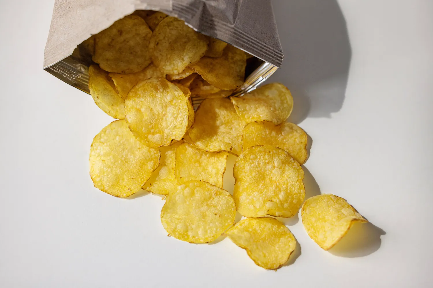 A person holding a bag of crispy potato chips.
