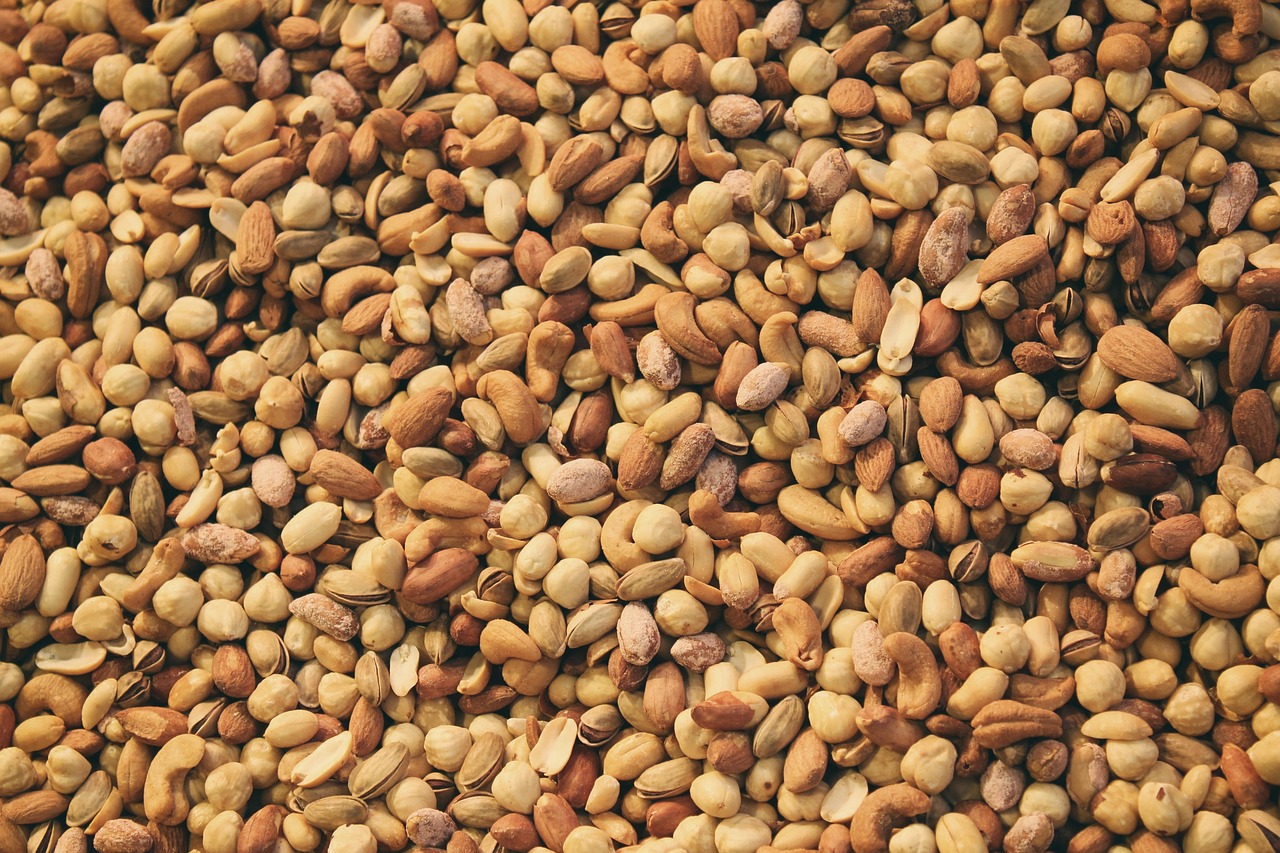 An assortment of raw nuts and seeds including almonds and pepitas on a wooden surface